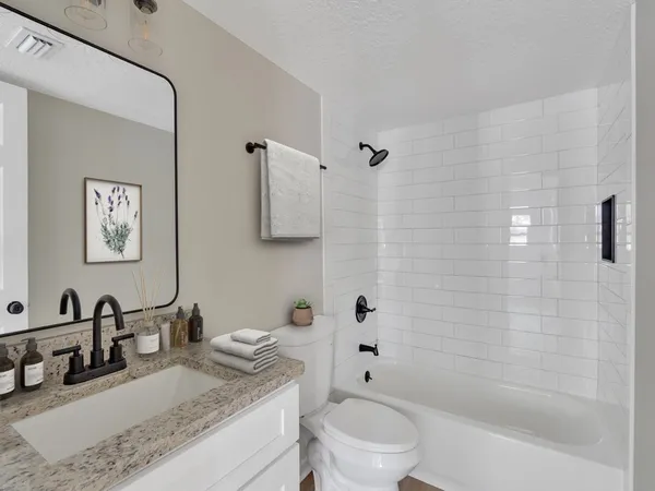 a bathroom with a granite countertop sink a toilet and shower