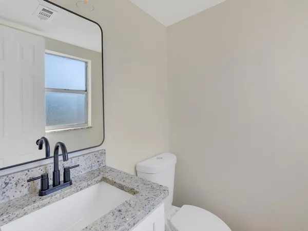 a bathroom with a granite countertop toilet sink and mirror