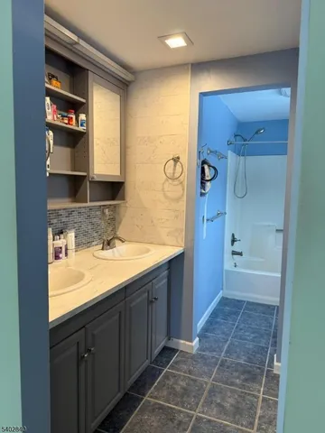 a bathroom with a granite countertop sink a mirror and a bathtub