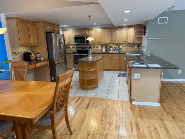 a kitchen with stainless steel appliances wooden floor dining table and chairs