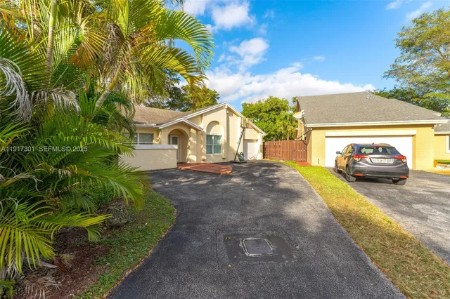 a view of a white house next to a yard with plants and trees