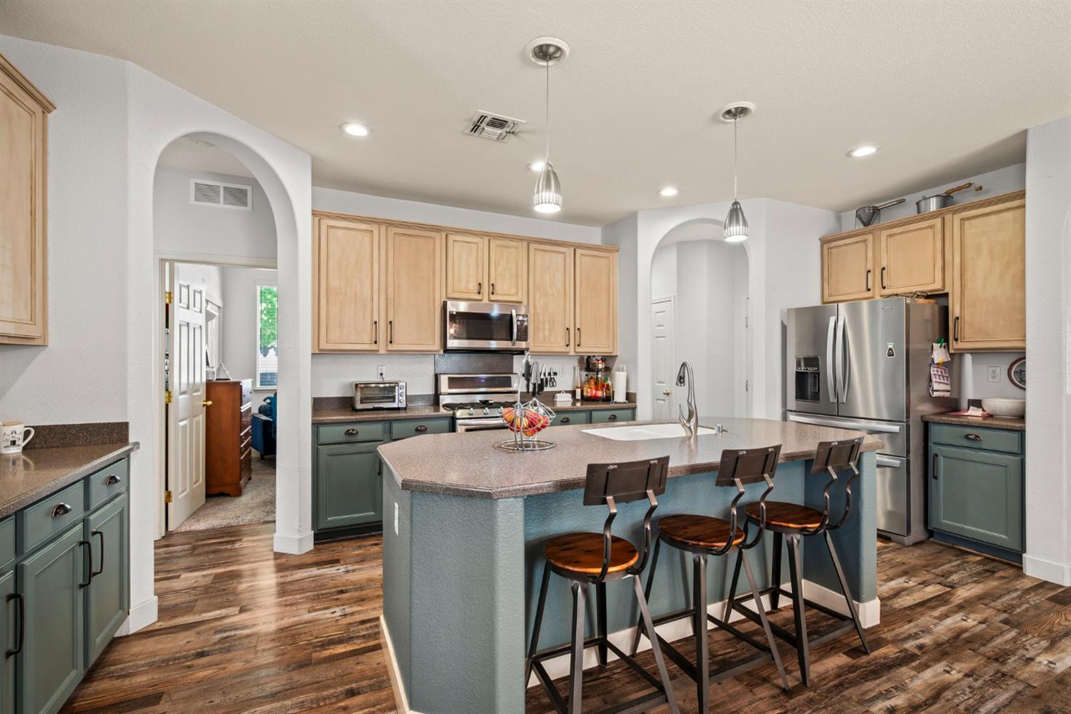 4403 Niobe Circle Rancho Cordova, CA 95742 - Photo 10 of 29 a kitchen with stainless steel appliances a refrigerator a stove top oven a sink dishwasher a dining table and chairs with wooden floor