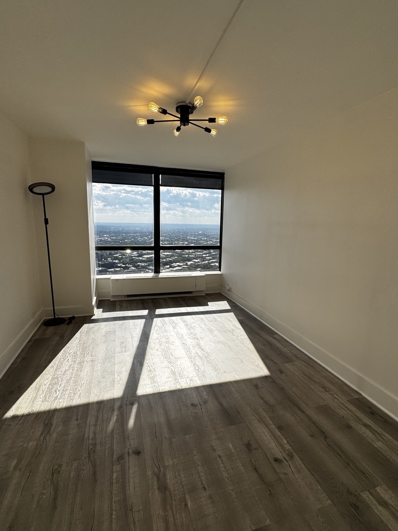 5415 North Sheridan Road, Unit 5414 Chicago, IL 60640 - Photo 13 of 18 an empty room with wooden floor and windows