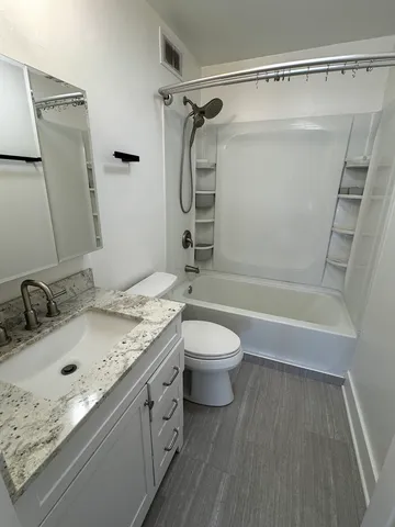 a bathroom with a granite countertop sink toilet and shower