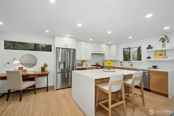 a kitchen with a dining table cabinets appliances and wooden floor