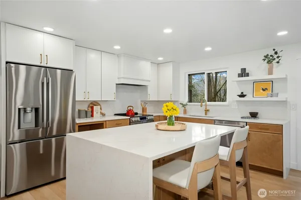 a kitchen with a refrigerator a stove a sink dishwasher with a dining table and chairs