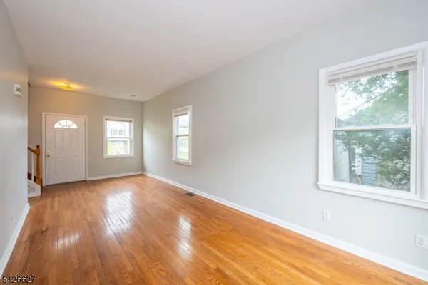 a view of empty room with window and wooden floor
