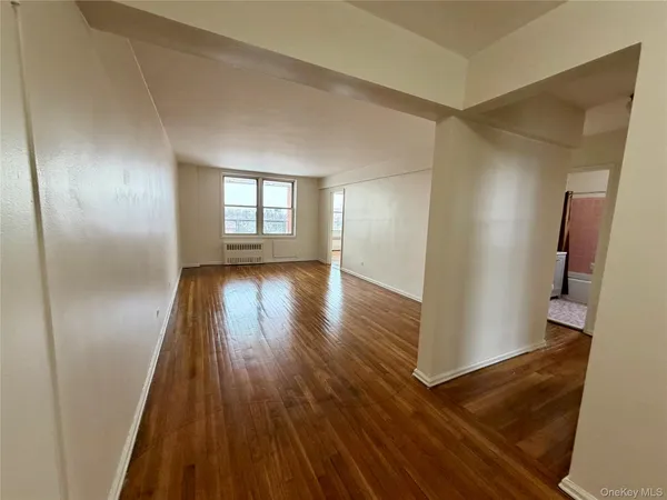an empty room with wooden floor and a window