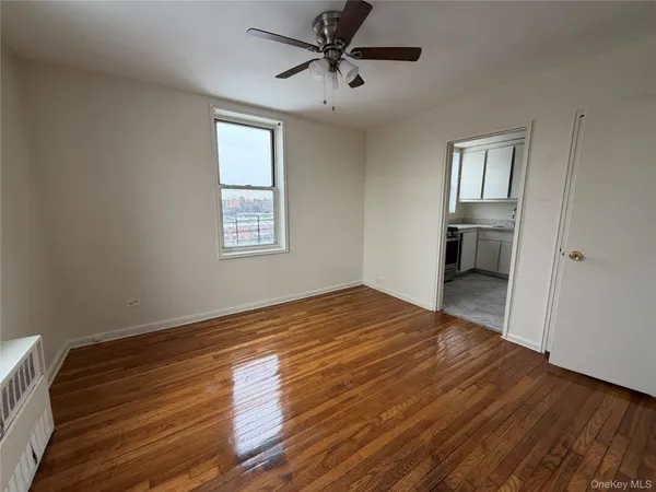 a view of empty room with wooden floor and fan