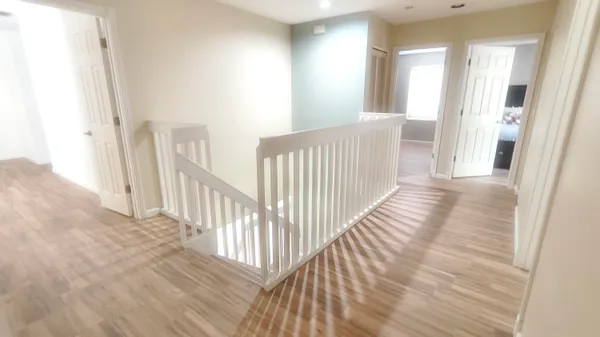 a view of a hallway with wooden floor and windows