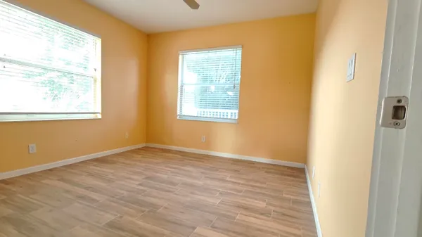 a view of an empty room with wooden floor and a window