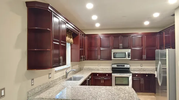 a kitchen with stainless steel appliances kitchen island granite countertop a refrigerator stove and oven