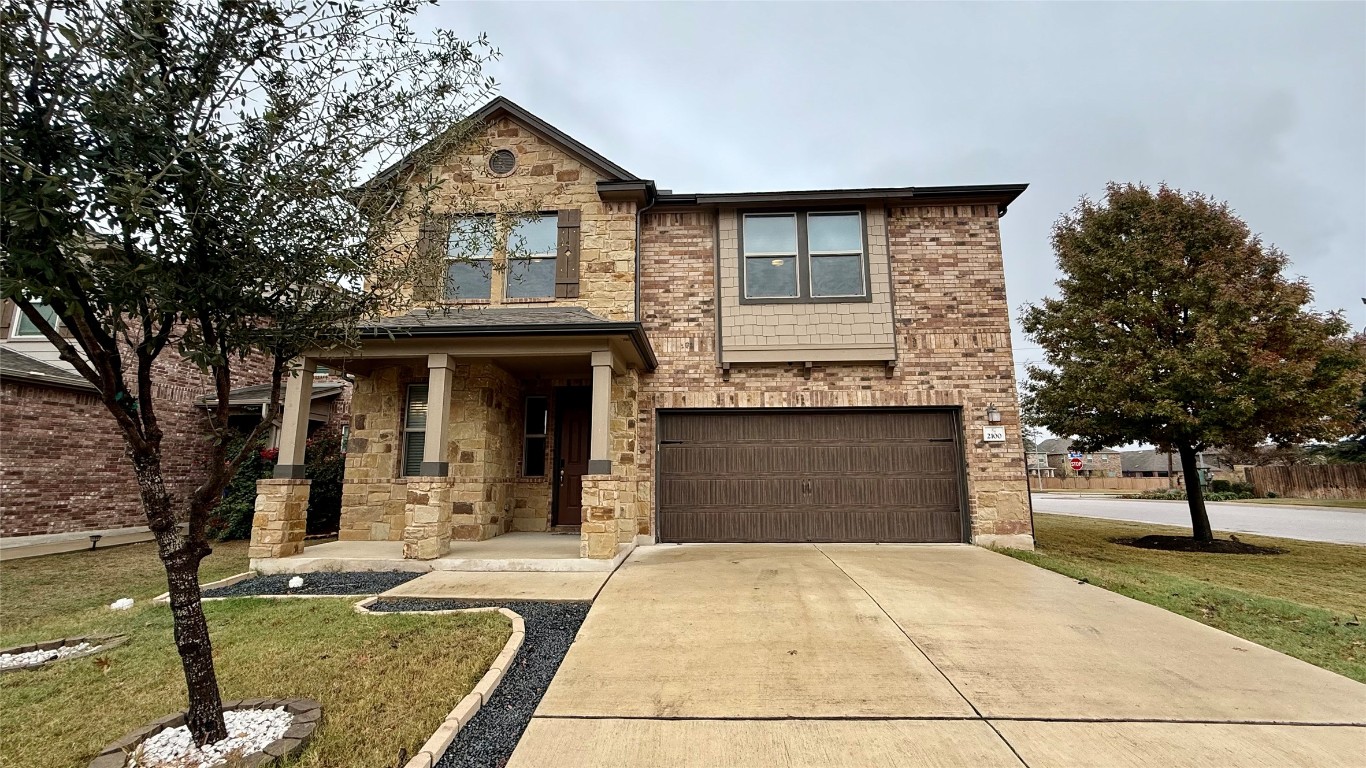 Craftsman inspired home featuring covered porch, driveway, a front lawn, a garage, and stone siding