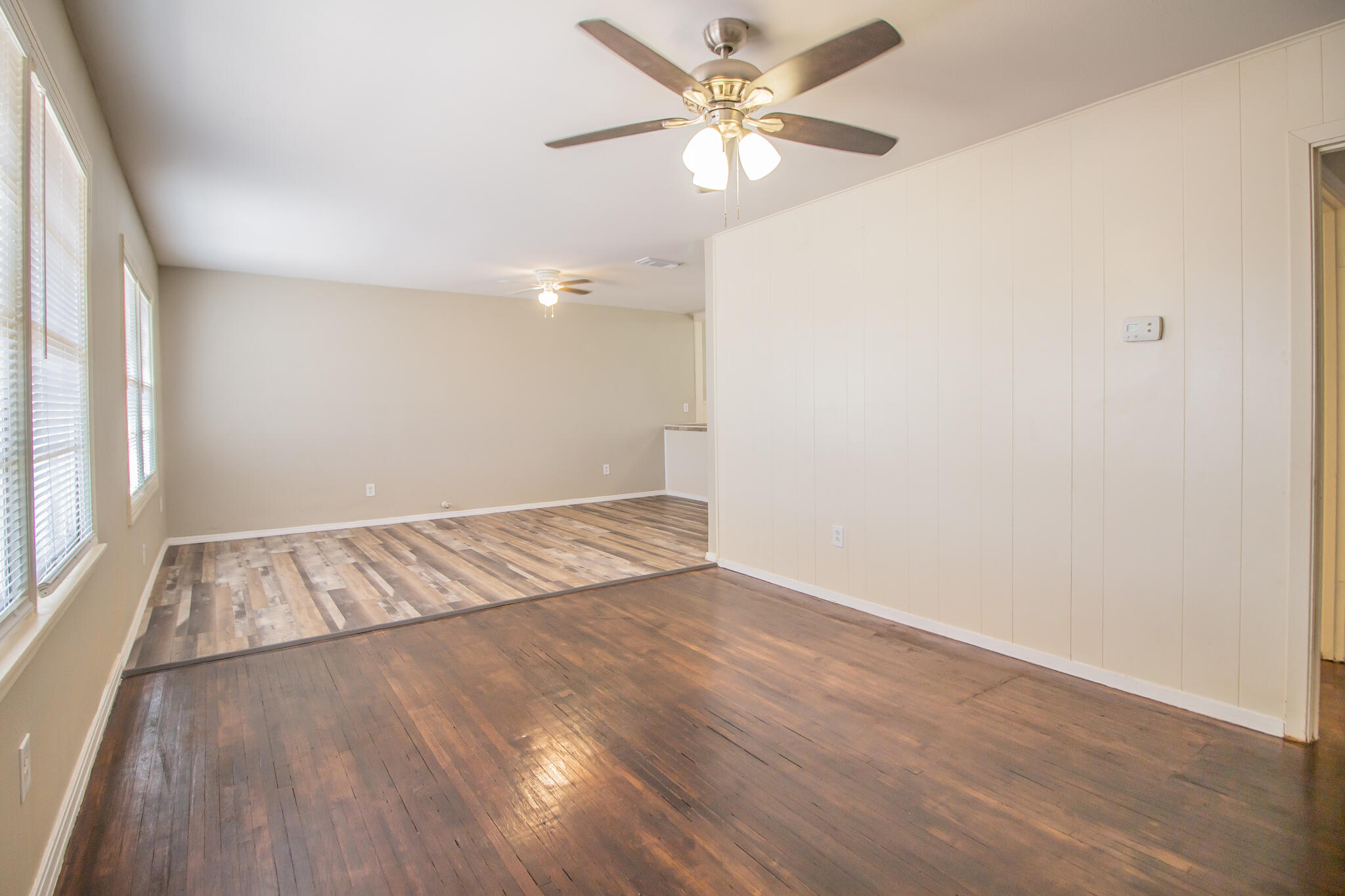 1304 42nd Street Lubbock, TX 79412 - Photo 4 of 17 an empty room with wooden floor fan and windows