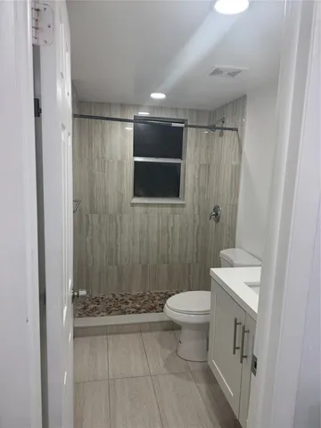 a bathroom with a toilet a sink a shower and a mirror