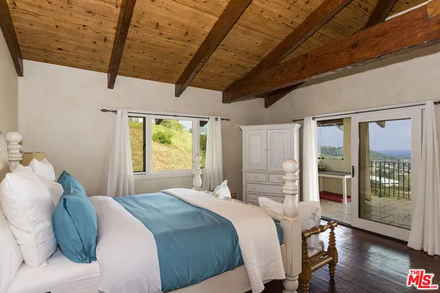 a bedroom with a bed wooden floor and window