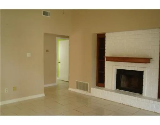 a view of an empty room with wooden floor and a fireplace