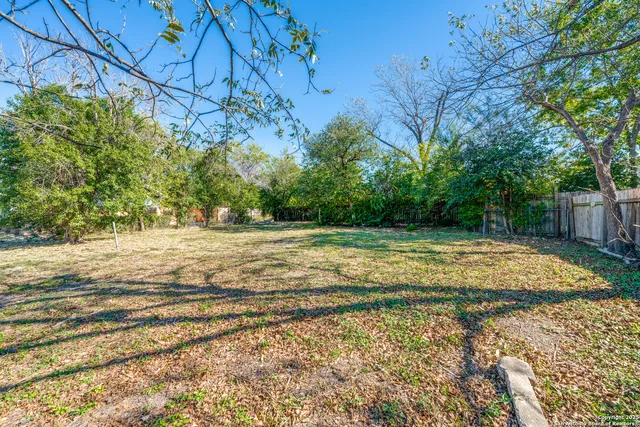 a view of a yard with wooden fence