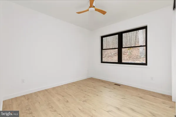an empty room with a window and ceiling fan