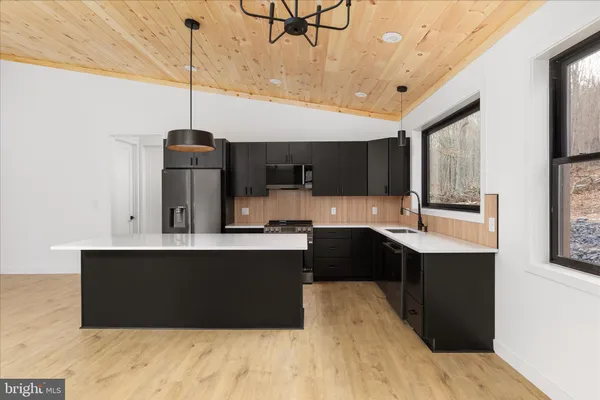 a kitchen with stainless steel appliances granite countertop a sink a stove and a wooden floors