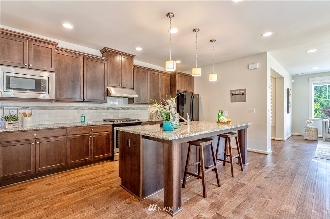 4521 185th Place Southeast Bothell, WA 98012 - Photo 7 of 33 a kitchen with kitchen island granite countertop wooden floor cabinets dining table and chairs