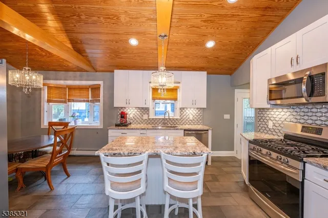 a kitchen with stainless steel appliances granite countertop a refrigerator a stove and white cabinets with wooden floors