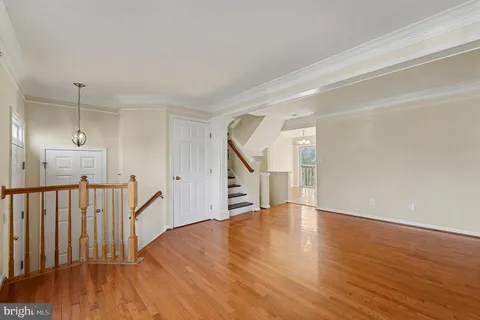 a view of an empty room with wooden floor and stairs