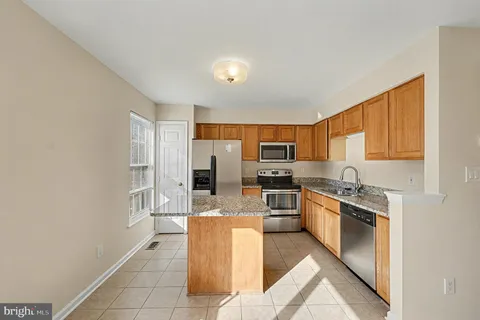 a kitchen with stainless steel appliances granite countertop a stove top oven a sink dishwasher a refrigerator and white cabinets with wooden floor