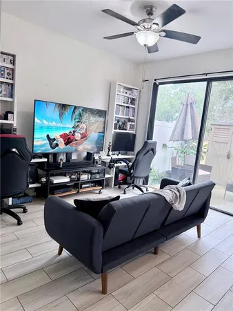 a living room with furniture a flat screen tv and a large window