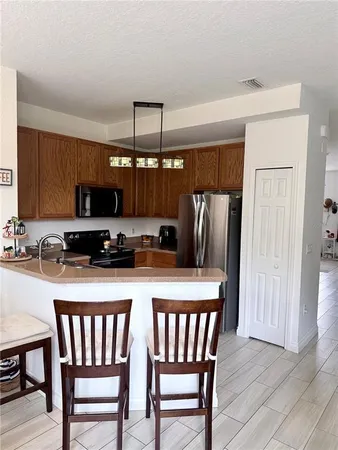 a kitchen with stainless steel appliances granite countertop a dining table chairs refrigerator and microwave