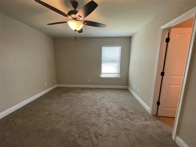 an empty room with a window and a fan