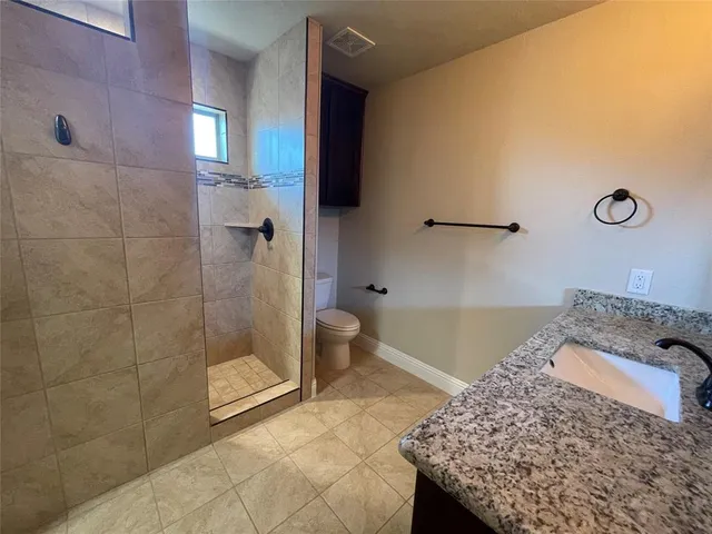 a bathroom with a granite countertop sink a toilet and shower