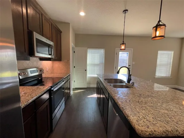 a kitchen with stainless steel appliances granite countertop a sink a stove top oven a counter space and cabinets