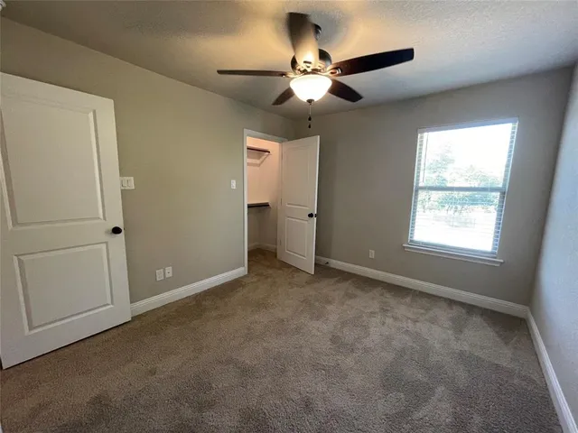en empty room with closet and a chandelier fan