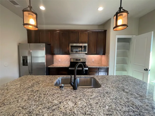 a kitchen with granite countertop a stove a sink and a refrigerator