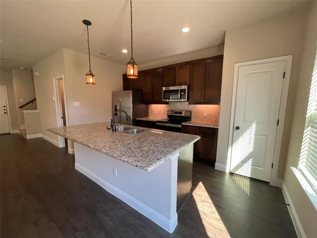 a large kitchen with kitchen island a wooden floor and a chandelier