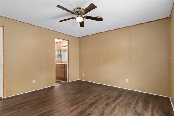 an empty room with wooden floor and a ceiling fan