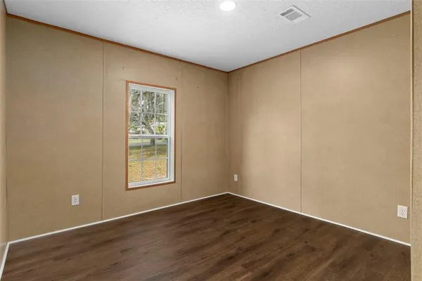 a view of an empty room with wooden floor and closet