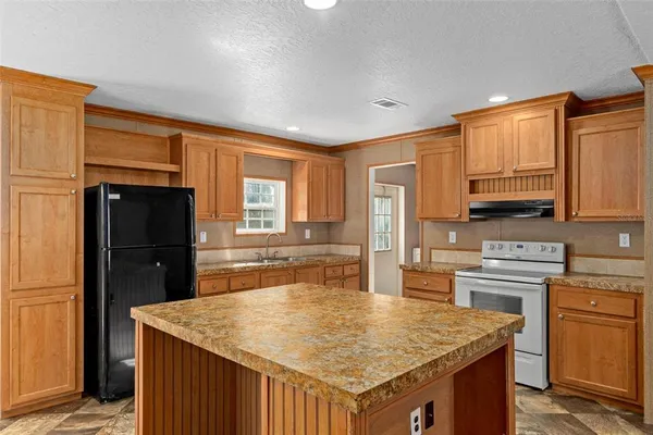a kitchen with stainless steel appliances granite countertop a stove a refrigerator a sink dishwasher and wooden cabinets with wooden floor