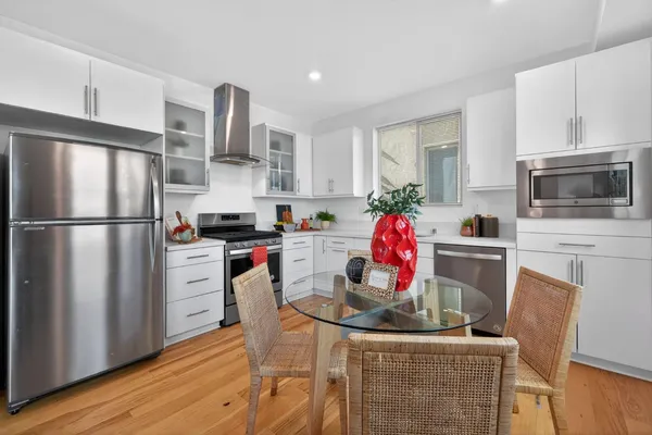 a kitchen with stainless steel appliances kitchen island granite countertop a refrigerator stove microwave and wooden floor