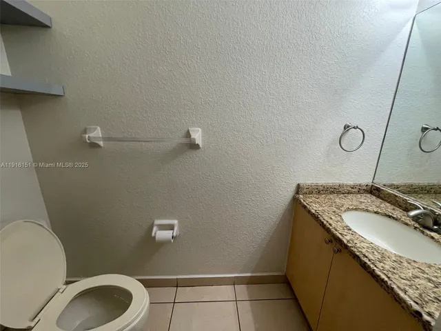 a bathroom with a granite countertop toilet sink and mirror