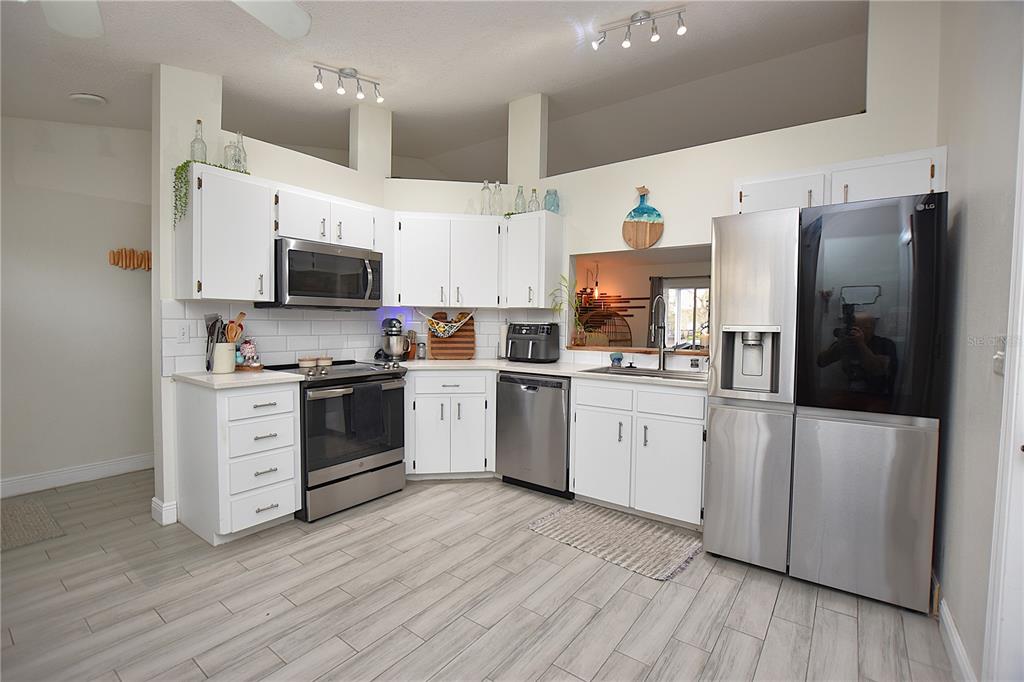 2022 Hatteras Point Lakeland, FL 33813 - Photo 5 of 36 a kitchen with white cabinets stainless steel appliances and wooden floor