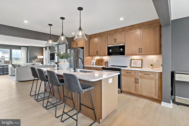 a kitchen with stainless steel appliances granite countertop a stove a sink a microwave a refrigerator a kitchen island with a dining table and chairs