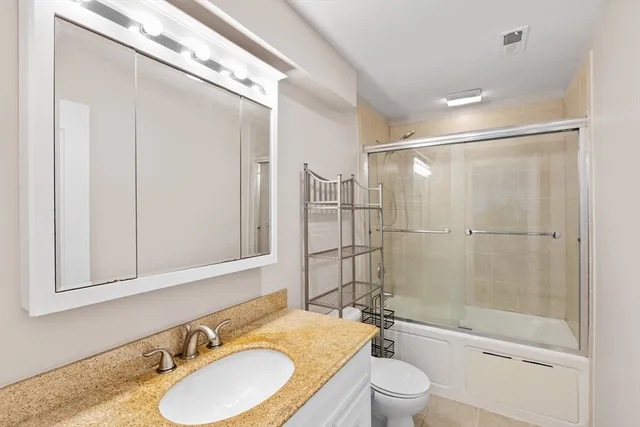 a bathroom with a granite countertop sink toilet a mirror and shower