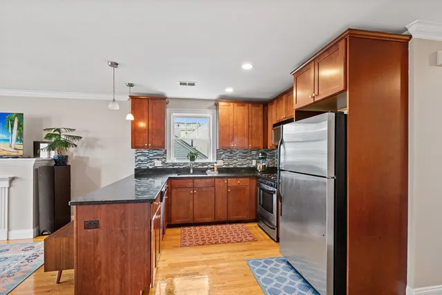 a kitchen with stainless steel appliances granite countertop a refrigerator a stove and a sink with wooden floor