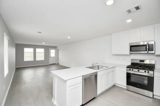 a view of a kitchen with sink microwave and cabinets