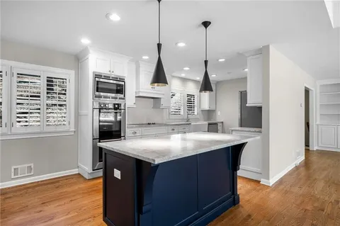 a kitchen with stainless steel appliances granite countertop a sink a stove and a wooden floors