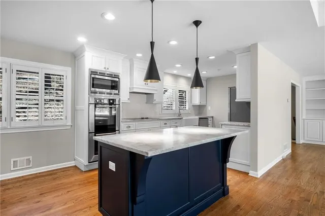 a kitchen with stainless steel appliances granite countertop a sink a stove and a wooden floors