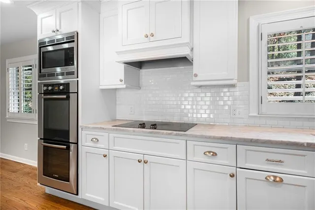 a kitchen with granite countertop white cabinets and stainless steel appliances