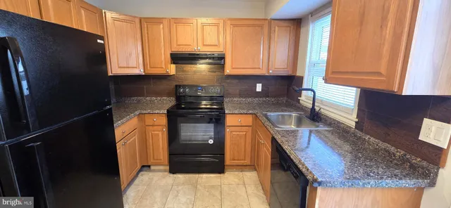 a kitchen with granite countertop a refrigerator a stove and a sink